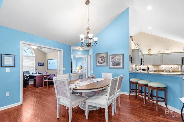 dining area with dark hardwood / wood-style flooring, lofted ceiling, sink, and a chandelier