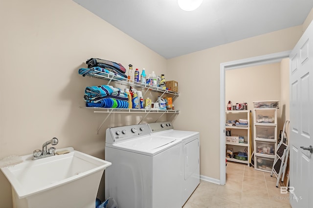 laundry area with light tile patterned floors, washing machine and dryer, and sink