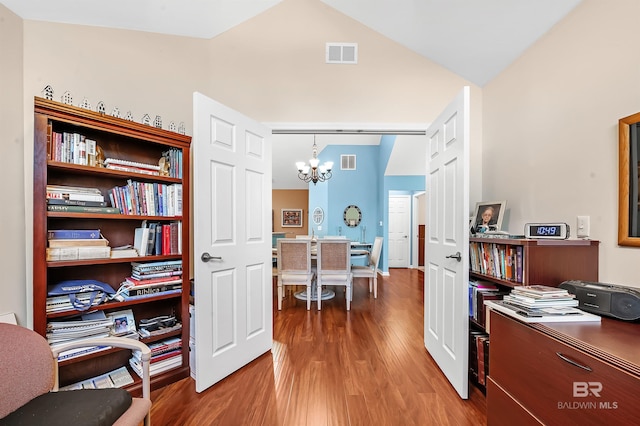 office with hardwood / wood-style flooring, vaulted ceiling, and a chandelier