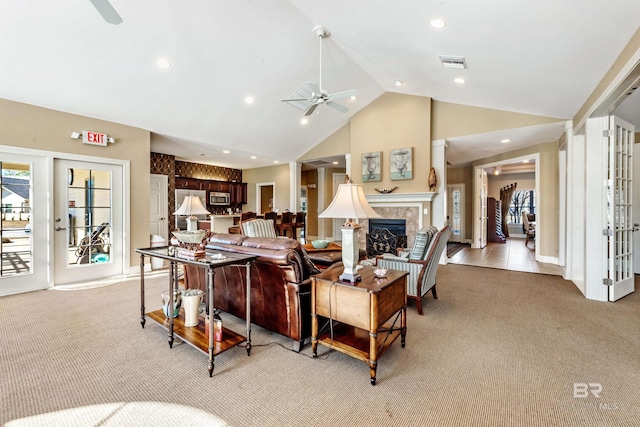 living room with ceiling fan, a fireplace, high vaulted ceiling, and light carpet