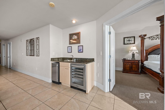 kitchen featuring beverage cooler, a sink, light tile patterned flooring, baseboards, and light colored carpet