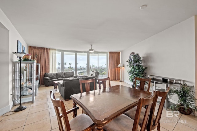 dining room with light tile patterned floors, baseboards, a wall of windows, and a ceiling fan