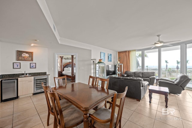dining area featuring light tile patterned floors, beverage cooler, wet bar, ceiling fan, and floor to ceiling windows