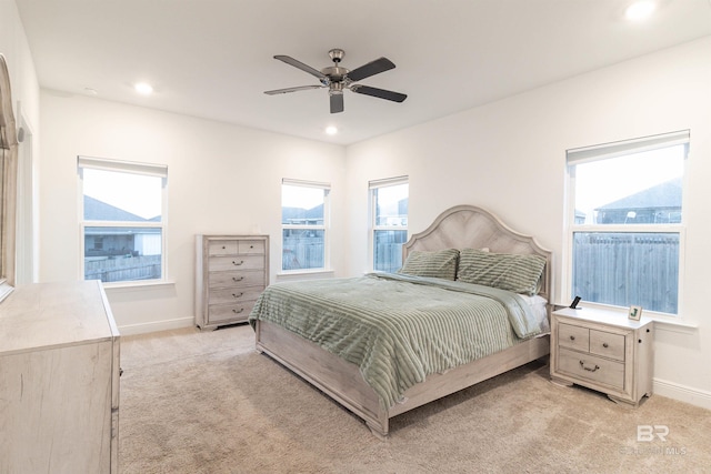 bedroom with light carpet, multiple windows, and ceiling fan