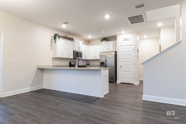 kitchen featuring kitchen peninsula, dark hardwood / wood-style flooring, white cabinetry, and stainless steel appliances