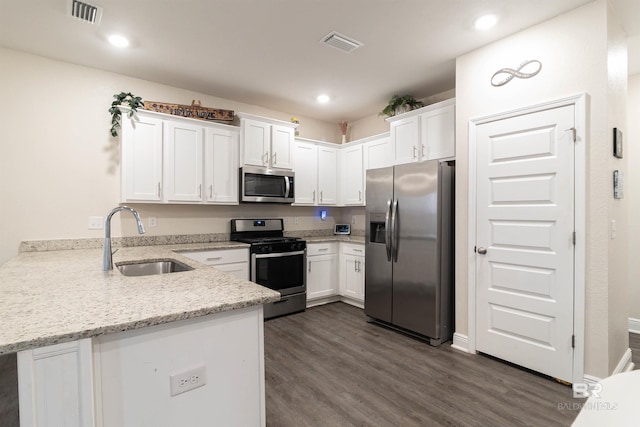 kitchen with white cabinetry, sink, stainless steel appliances, light stone counters, and kitchen peninsula