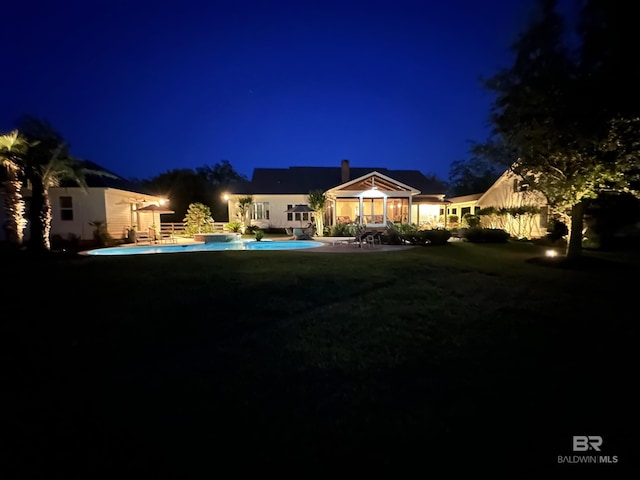 view of front of property featuring an outdoor pool, a patio area, a chimney, and a yard