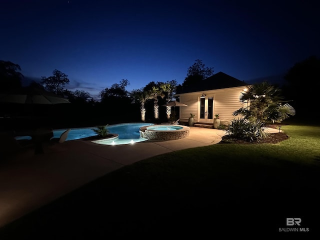 pool at night featuring french doors, a patio, and a pool with connected hot tub