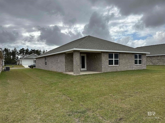 rear view of house with a garage, a yard, a patio, and central AC unit