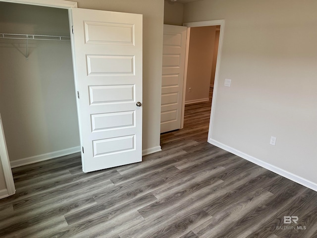 unfurnished bedroom with a closet and dark hardwood / wood-style floors