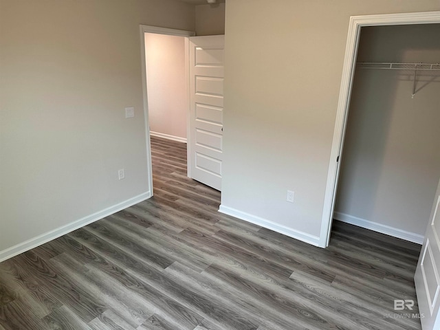 unfurnished bedroom with dark wood-type flooring and a closet