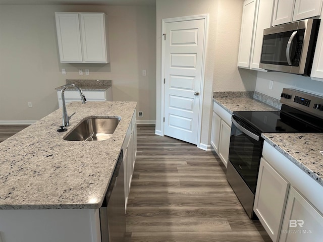 kitchen with dark hardwood / wood-style floors, stainless steel appliances, a center island with sink, sink, and white cabinets