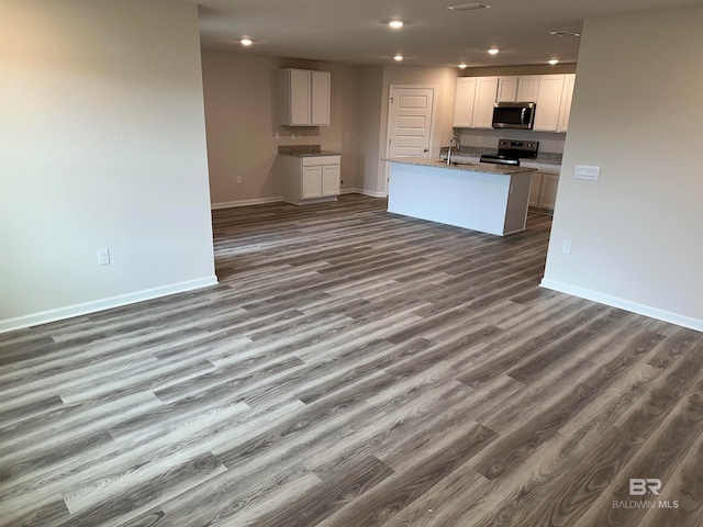 kitchen with white cabinetry, hardwood / wood-style flooring, stainless steel appliances, and a center island with sink