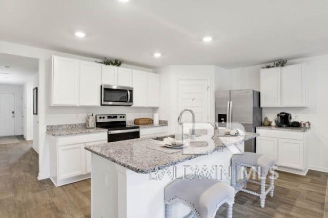 kitchen featuring white cabinets, a kitchen island with sink, stainless steel appliances, and wood-type flooring