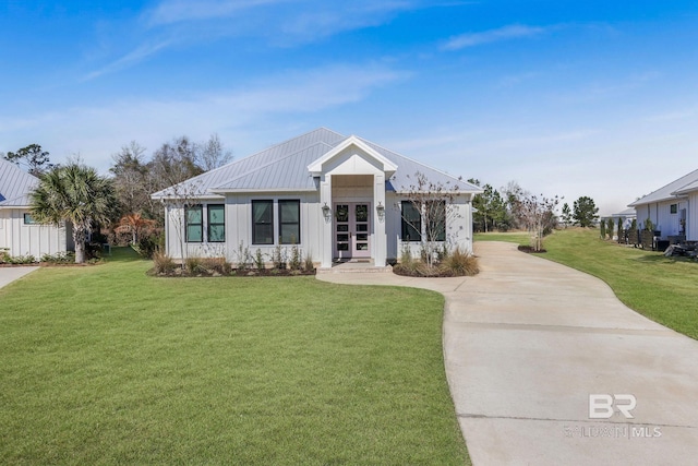 modern farmhouse style home with french doors, concrete driveway, board and batten siding, a front yard, and metal roof