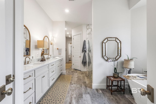 bathroom with double vanity, a sink, and wood finished floors