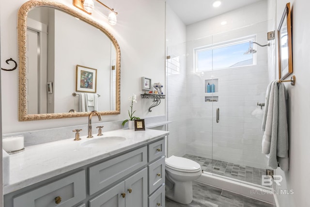 bathroom featuring toilet, a stall shower, and vanity