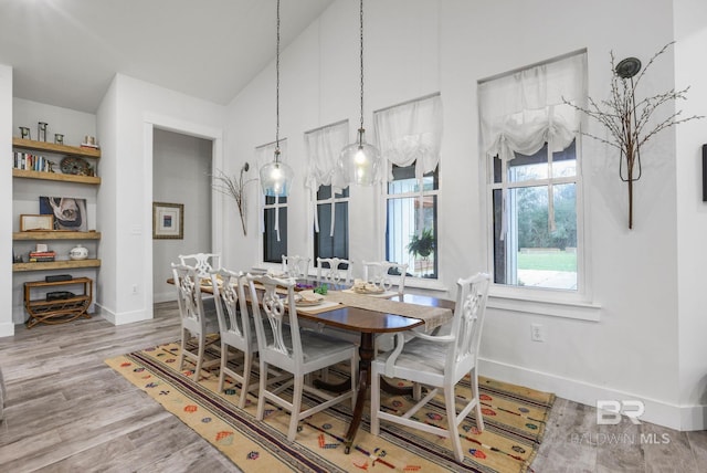 dining space with high vaulted ceiling, wood finished floors, and baseboards