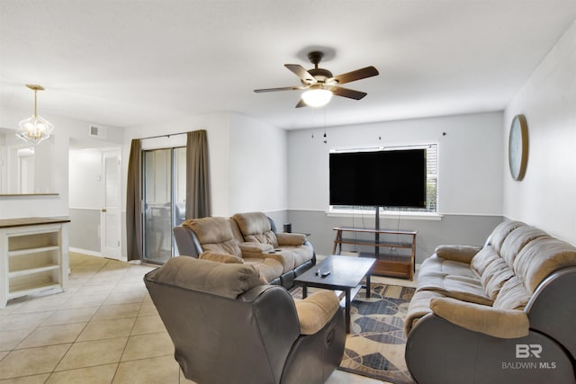 tiled living room with ceiling fan with notable chandelier