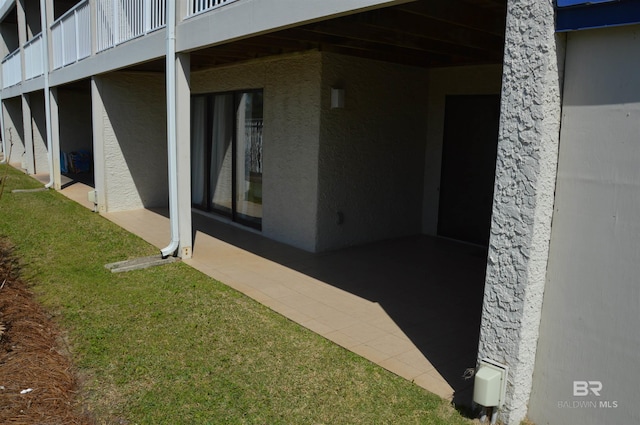 view of side of property featuring a lawn, a patio, and stucco siding