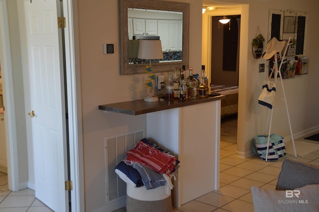 interior space featuring light tile patterned floors, baseboards, and visible vents