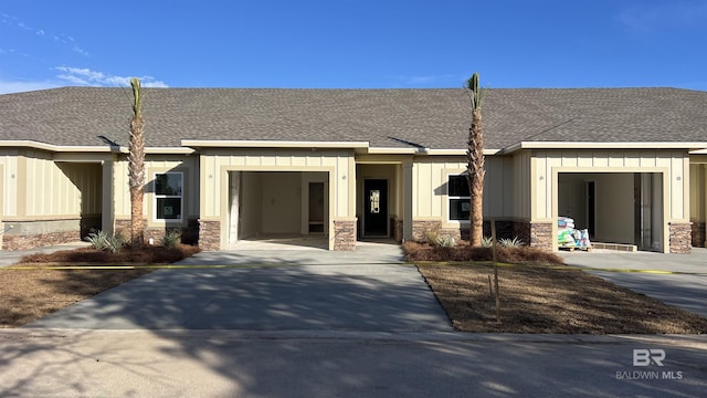 view of front facade with a garage, stone siding, board and batten siding, and concrete driveway