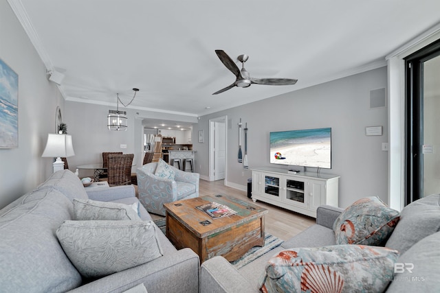 living room featuring crown molding, ceiling fan with notable chandelier, and light wood-type flooring