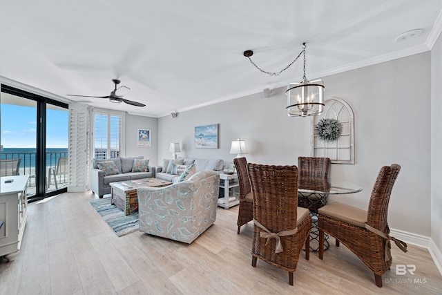 living room with ceiling fan with notable chandelier, a water view, light hardwood / wood-style flooring, ornamental molding, and a wall of windows