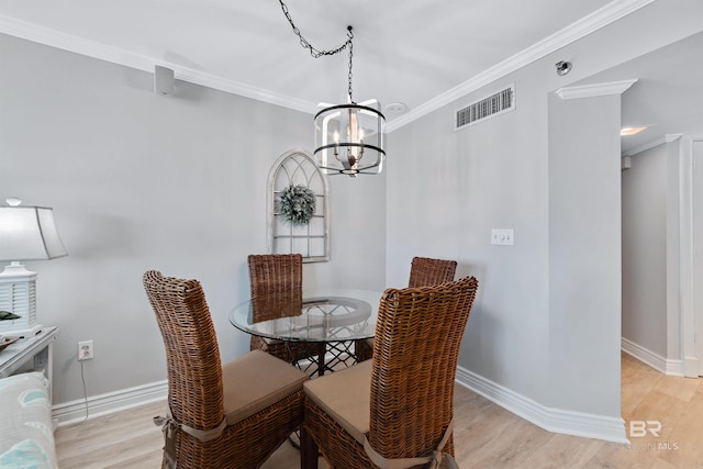 dining area featuring light wood-type flooring, crown molding, and a notable chandelier