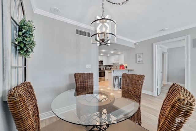 dining room featuring sink, ornamental molding, light hardwood / wood-style flooring, and a chandelier