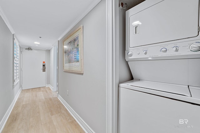 clothes washing area featuring light wood-type flooring, stacked washer / dryer, and ornamental molding