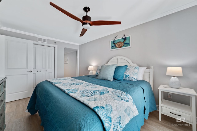 bedroom featuring ceiling fan, light hardwood / wood-style floors, ornamental molding, and a closet