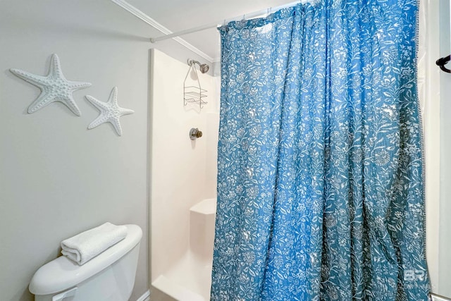 bathroom featuring toilet, ornamental molding, and walk in shower