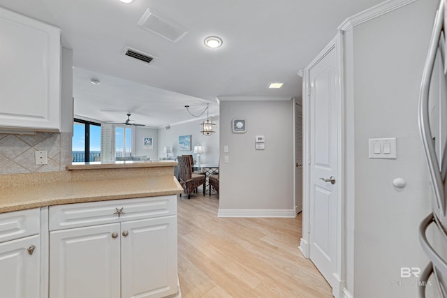 kitchen featuring hanging light fixtures, light hardwood / wood-style floors, decorative backsplash, white cabinets, and ceiling fan with notable chandelier