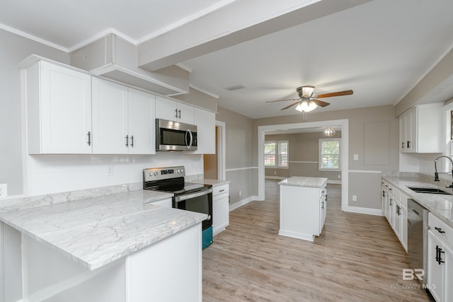 kitchen featuring white cabinets, sink, a kitchen island, light stone counters, and stainless steel appliances