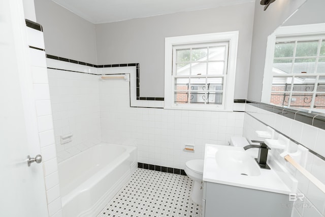 bathroom with a bathtub, vanity, tile walls, and toilet