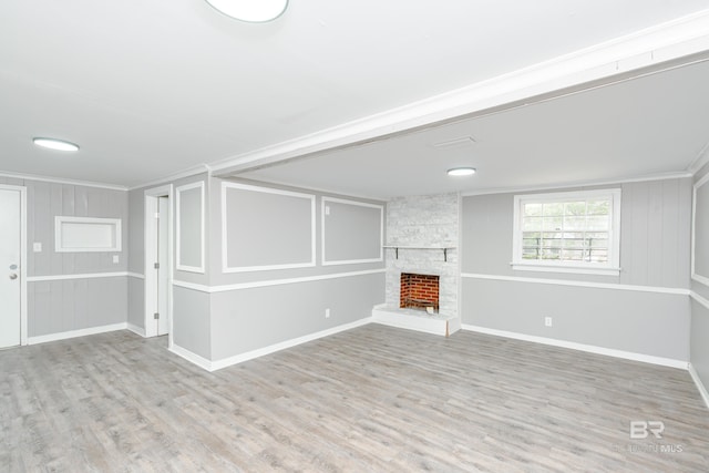 unfurnished living room featuring a stone fireplace, light wood-type flooring, and crown molding