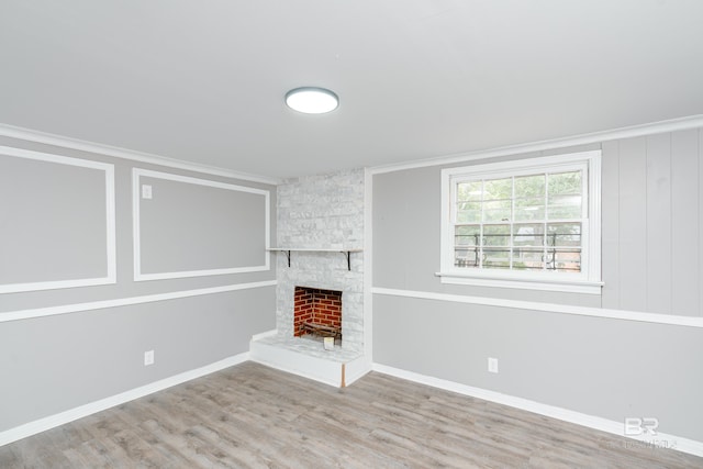 unfurnished living room with hardwood / wood-style floors, a stone fireplace, and ornamental molding