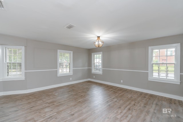 empty room with light wood-type flooring and a notable chandelier