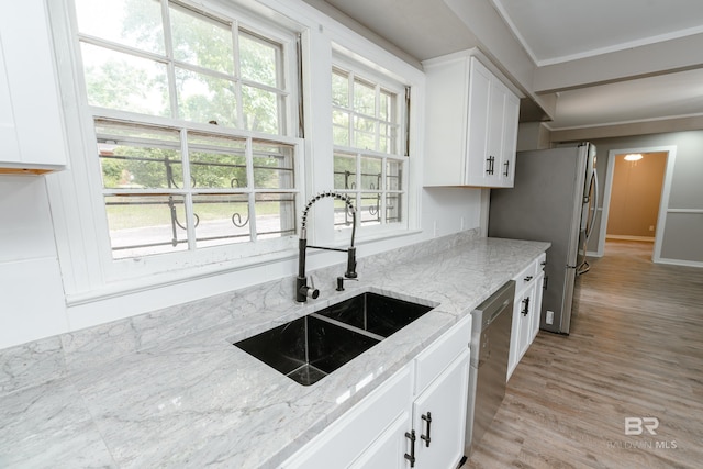 kitchen with sink, light stone countertops, ornamental molding, appliances with stainless steel finishes, and white cabinetry