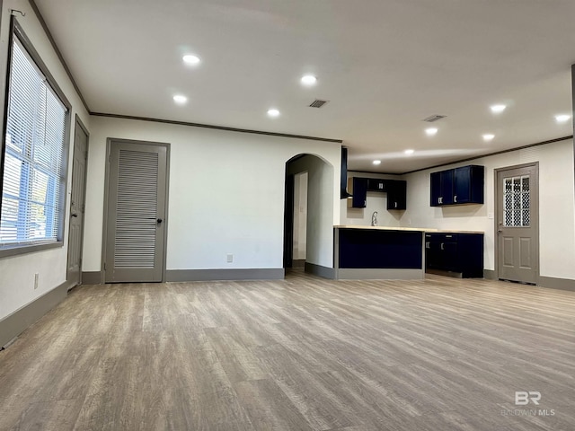 unfurnished living room featuring hardwood / wood-style flooring, ornamental molding, and sink