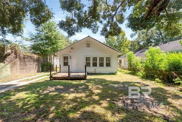 back of property with a deck and a lawn