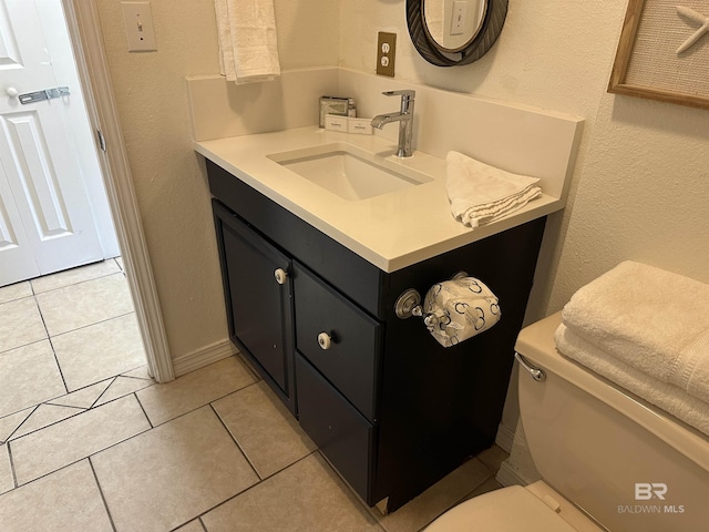 half bathroom with toilet, a textured wall, vanity, and tile patterned floors