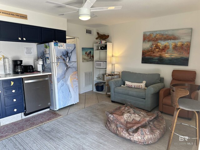 kitchen featuring white appliances, blue cabinetry, ceiling fan, and tile floors