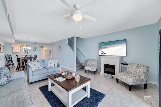 living room with light tile patterned flooring and ceiling fan with notable chandelier