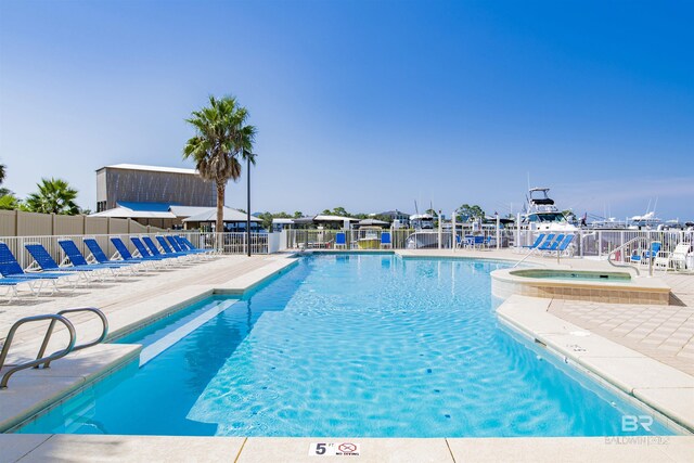 view of pool with a patio area, a water view, and a hot tub