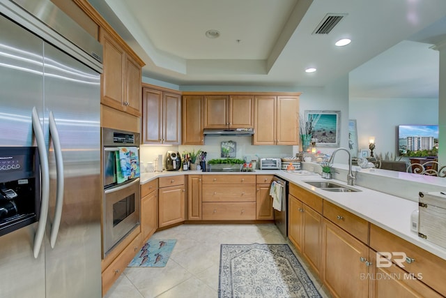 kitchen with light tile patterned floors, stainless steel appliances, a tray ceiling, and sink