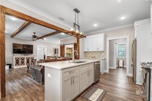 kitchen featuring pendant lighting, sink, a barn door, an island with sink, and white cabinetry