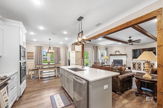 kitchen featuring stainless steel appliances, a kitchen island with sink, sink, pendant lighting, and a fireplace