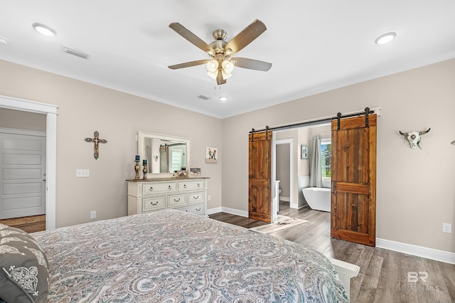 bedroom featuring light wood-type flooring, a barn door, and ceiling fan